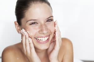 Woman scrubbing sugar on her face --- Image by © GretaMarie/cultura/Corbis